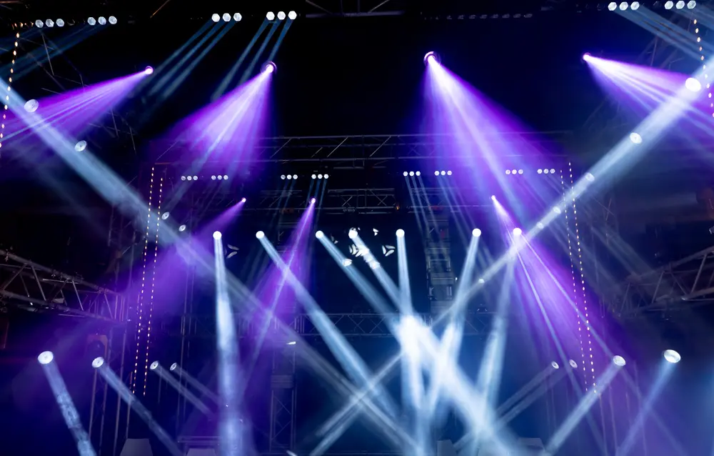 Stage lights crisscrossing in beams across a wide stage.